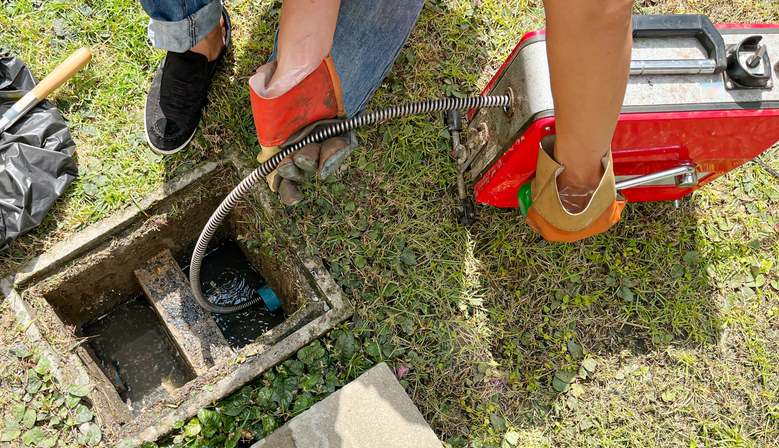 A worker using a drain cleaning machine outdoors in Visalia, CA