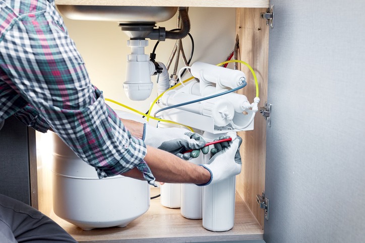 Plumber installing a water filtration system under the sink in Visalia, CA