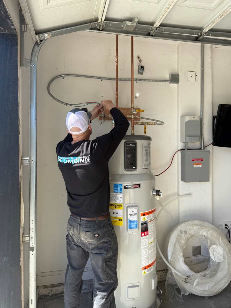 Plumber installing a water heater in a garage setting in Visalia, CA