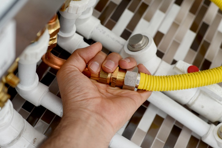 Hand connecting a flexible gas line to household piping in Visalia, CA